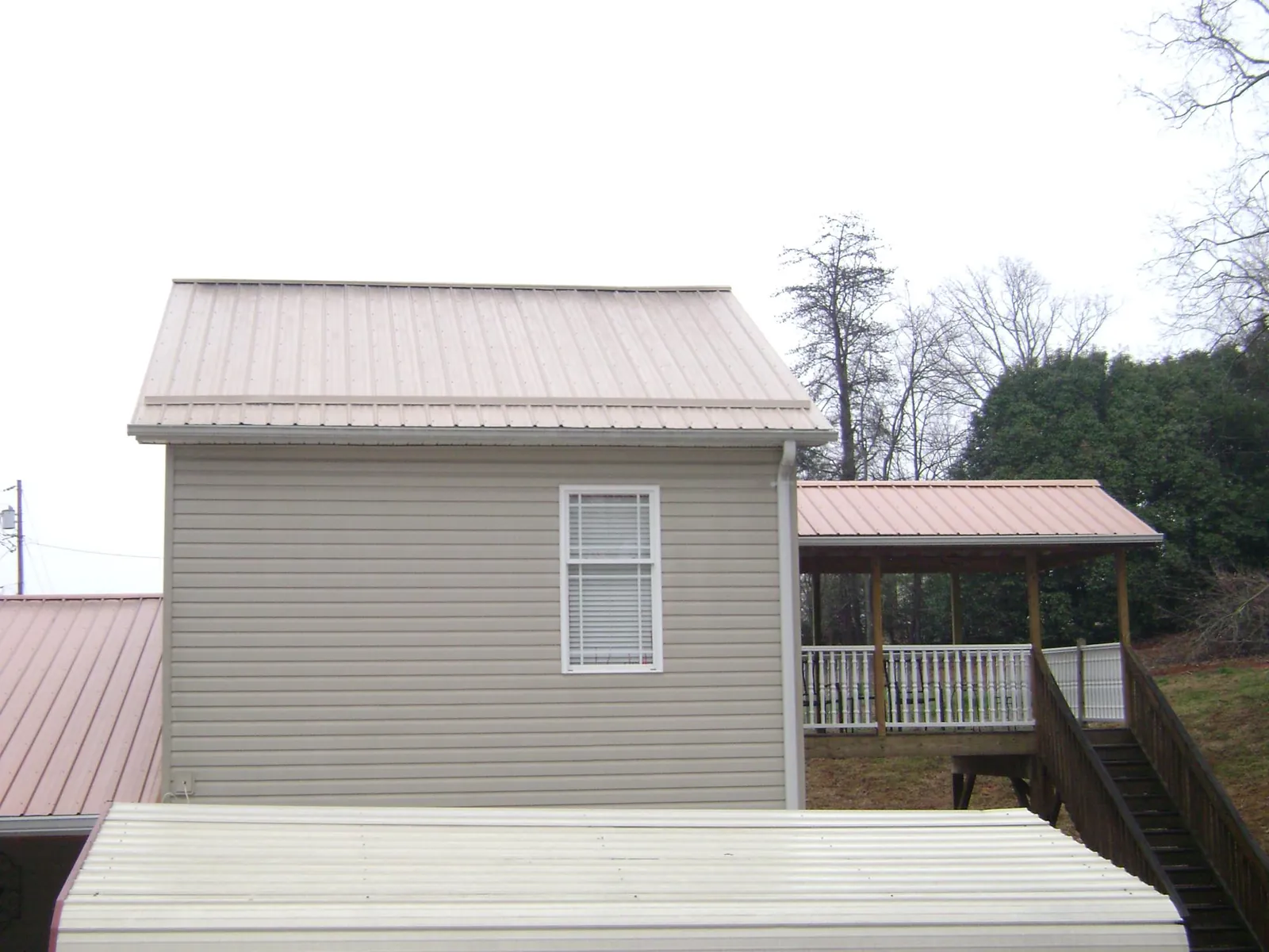 Tan metal roofs on a two story addition and attached porch, from a Roof Replacement job in Heislerville