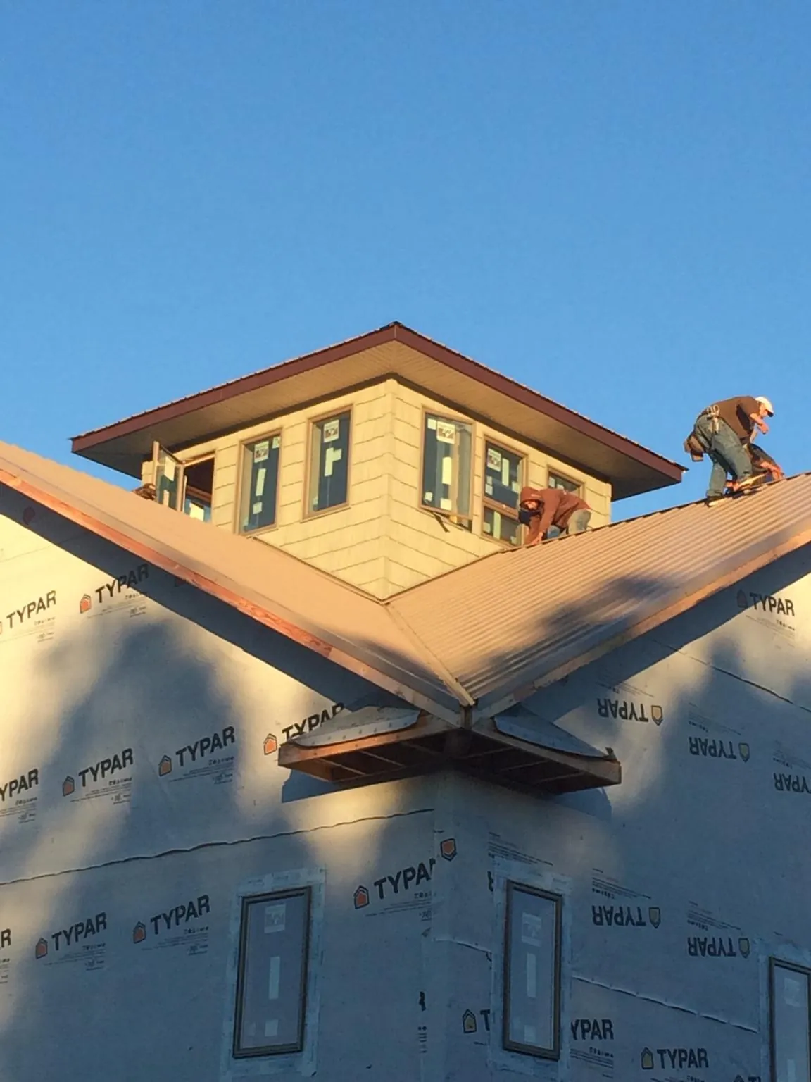 Roofers working around a rooftop cupola on a new metal roof at sunset — Roof Waterproofing in Heislerville by Roofing Brothers